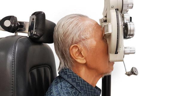 一位老人在医院里看视光师的侧视,同时用一镜检查眼睛